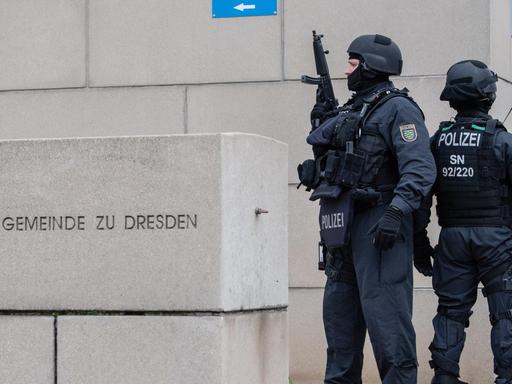 Zwei stark bewaffnete Polizisten stehen vor der Jüdischen Gemeinde zu Dresden.