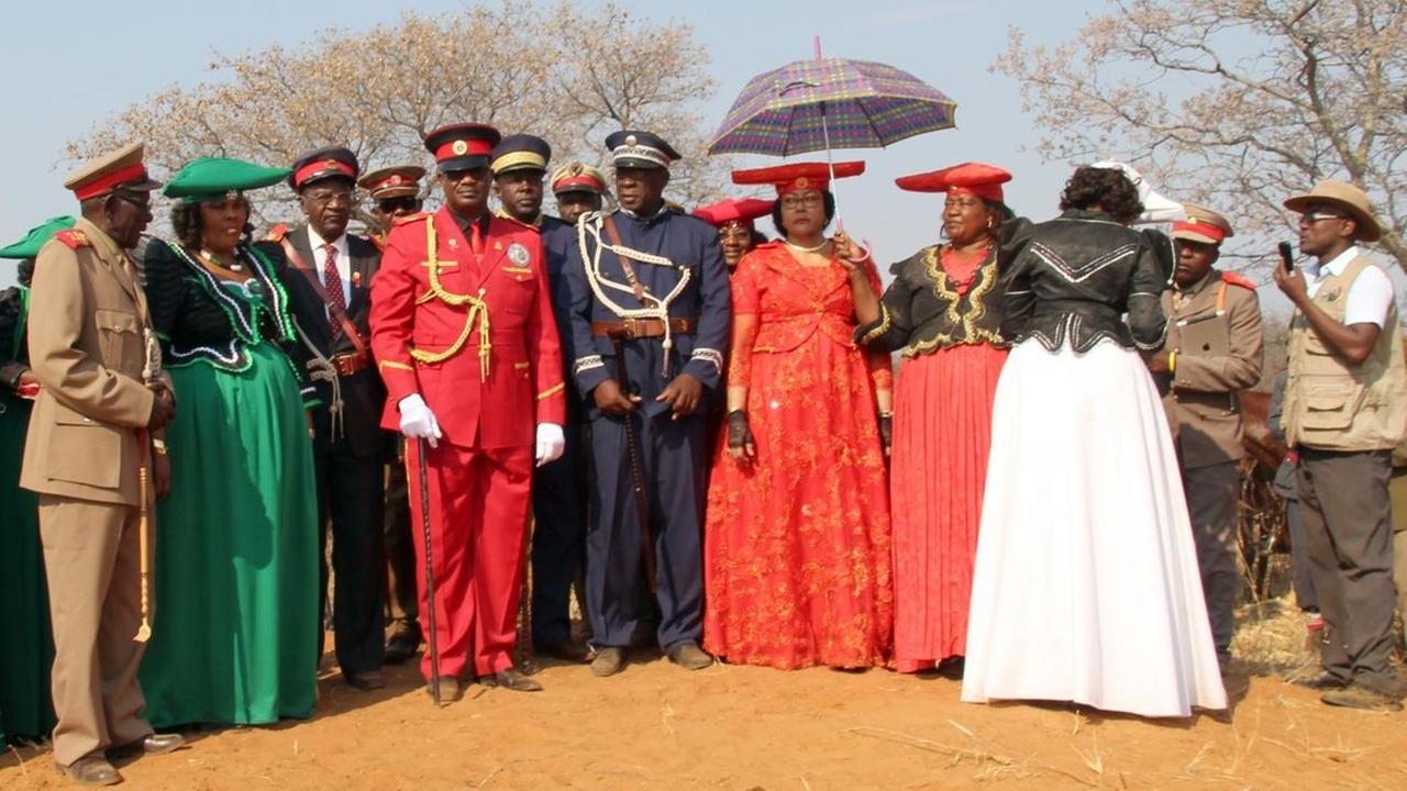Stammesoberhaupt Chief Vekuii Rukoro (M, rote Uniform) und andere örtliche Stammesältere stehen auf dem Hügel, von dem aus der damalige deutsche Generalleutnant Lothar von Trotha den Schießbefehl gab, der den Beginn des Völkermordes an den Herero markierte. Stammesoberhaupt Chief Vekuii Rukoro (M, rote Uniform) und andere örtliche Stammesältere stehen auf dem Hügel, von dem aus der damalige deutsche Generalleutnant Lothar von Trotha den Schießbefehl gab, der den Beginn des Völkermordes an den Herero markierte.