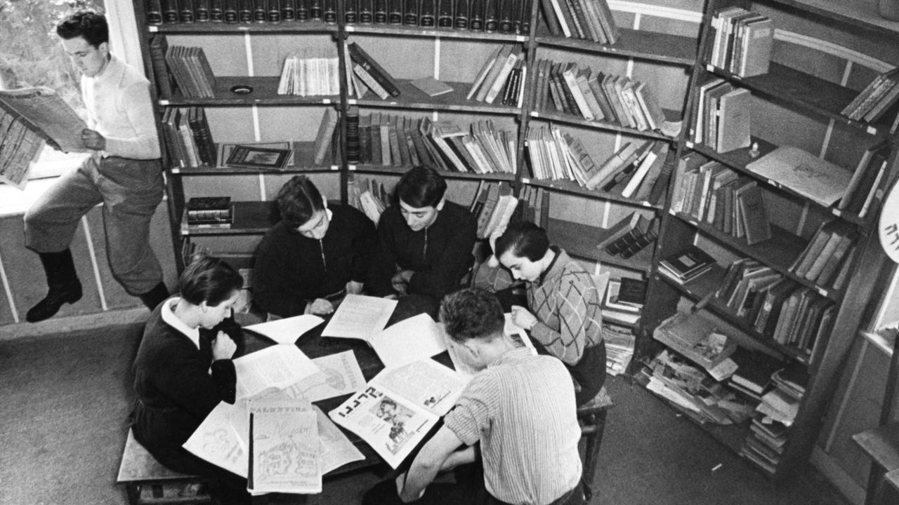Jugendliche lesen an einem Tisch im Gemeinschaftsraum. Jugendliche lesen an einem Tisch im Gemeinschaftsraum.