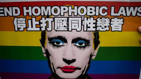 Ein Plakat mit der Aufschrift "End homophobic laws" zeigt einen wie eine Dragqueen geschminkten Wladimir Putin, im Hintergrund die Regenbogenflagge als Symbol der homosexuellen Bewegung.