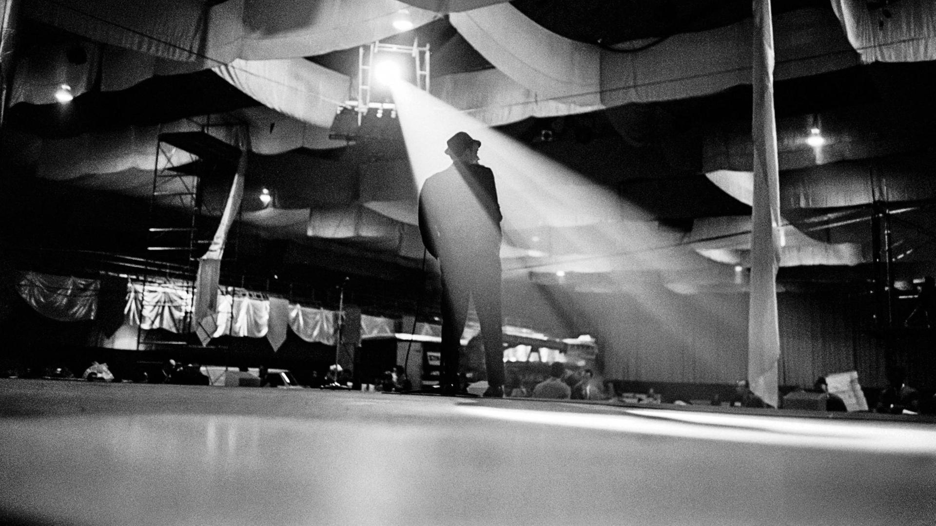 Frank Sinatra mit dem Rücken zur Kamera auf einer leeren Bühne im Scheinwerferlicht