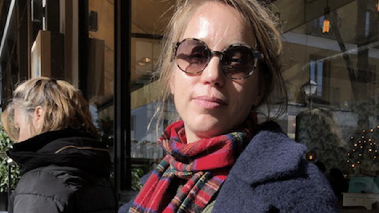 Katja Bigalke sitzt vor einem Café in der Sonne.