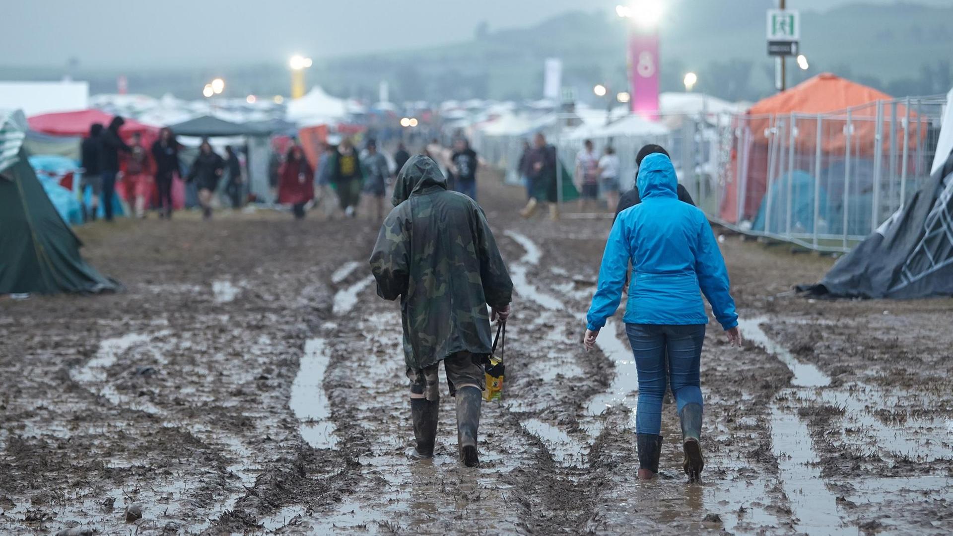 Festivalbesucher gehen am 03.06.2016 beim Festival "Rock am Ring" nach einem Gewitterregen über das aufgeweichte Gelände. Festivalbesucher gehen am 03.06.2016 beim Festival "Rock am Ring" nach einem Gewitterregen über das aufgeweichte Gelände.