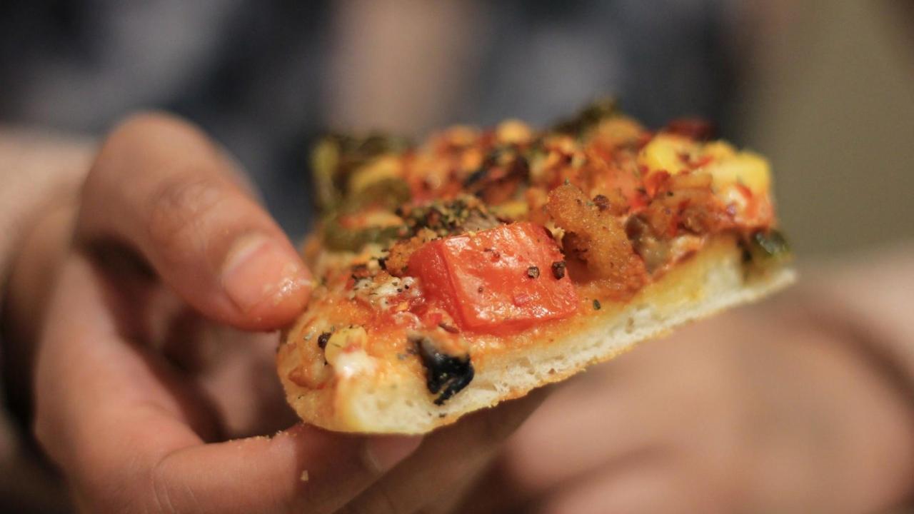 Ein Mädchen hält ein Stück Pizza in der Hand. Ein Mädchen hält ein Stück Pizza in der Hand.