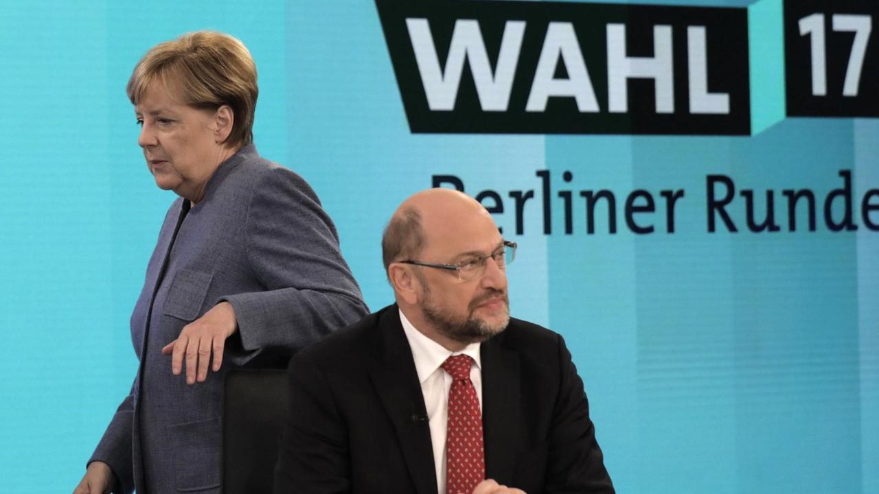 Bundeskanzlerin Angela Merkel (CDU) geht hinter dem SPD-Vorsitzenden Martin Schulz am 24.09.2017 in Berlin vor einer Fernsehrunde der Parteivorsitzenden nach der Bundestagswahl vorbei. 