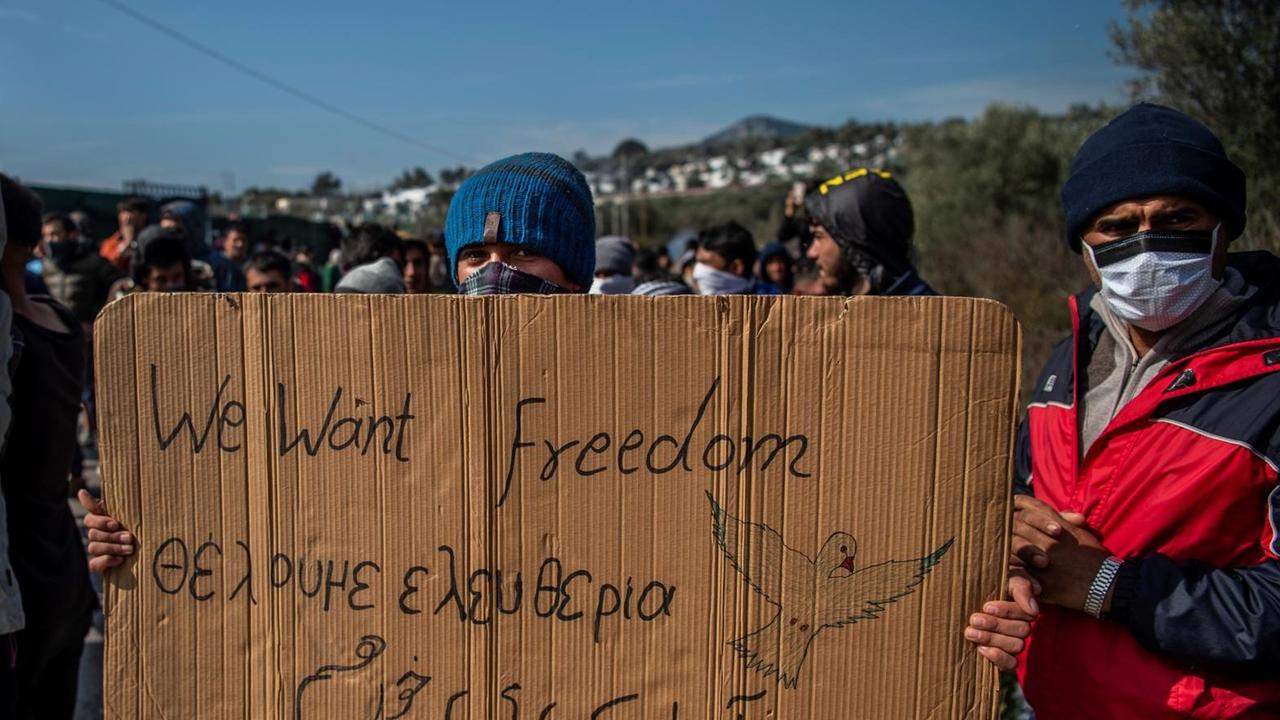 Ein Flüchtling hält ein Transparent mit dem Satz "we want freedom" in den Händen Ein Flüchtling hält ein Transparent mit dem Satz "we want freedom" in den Händen