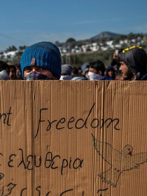 Ein Flüchtling hält ein Transparent mit dem Satz "we want freedom" in den Händen