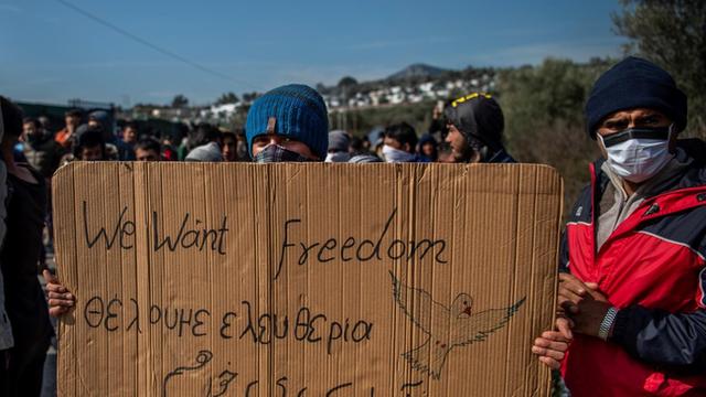 Ein Flüchtling hält ein Transparent mit dem Satz "we want freedom" in den Händen