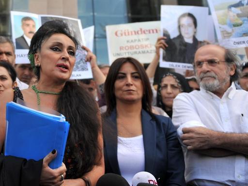 Eren Keskin, die frühere Chefredakteurin der türkischen Zeitung "Özgür Gündem" spricht in Istanbul mit Pressevertretern, während kurdische Frauen Fotos inhaftierter Journalisten zeigen.