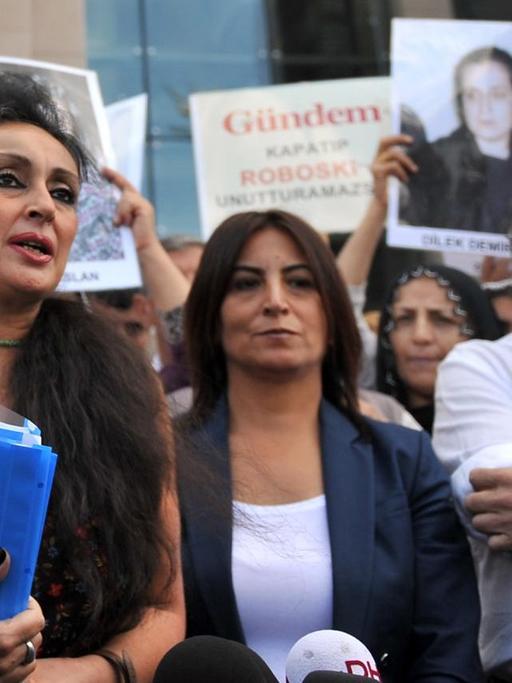 Eren Keskin, die frühere Chefredakteurin der türkischen Zeitung "Özgür Gündem" spricht in Istanbul mit Pressevertretern, während kurdische Frauen Fotos inhaftierter Journalisten zeigen.