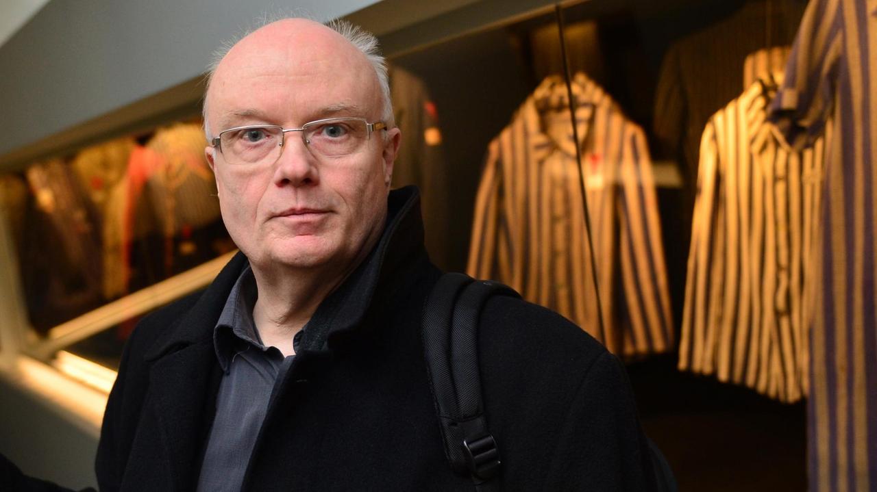 Volkhard Knigge, Direktor der Stiftung Buchenwald und Mittelbau-Dora. Ein Mann steht vor einer Vitrine mit Häftlingskleidung. Volkhard Knigge, Direktor der Stiftung Buchenwald und Mittelbau-Dora. Ein Mann steht vor einer Vitrine mit Häftlingskleidung.