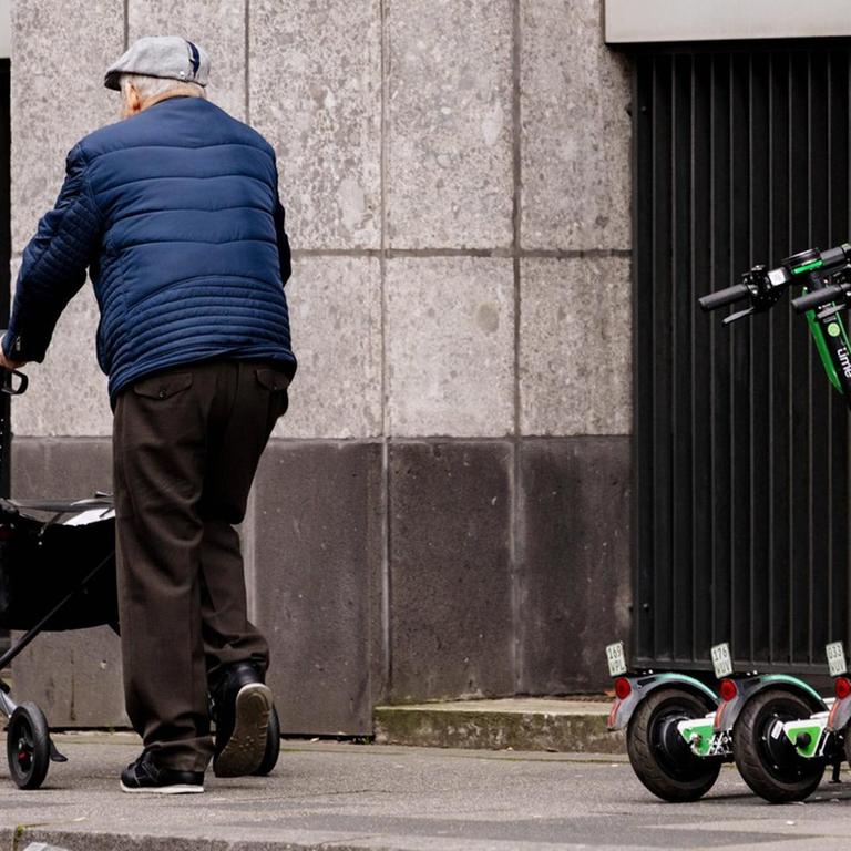 Rentner mit Rollator passiert E-Scooter der Firma Lime in der Kölner Innenstadt.