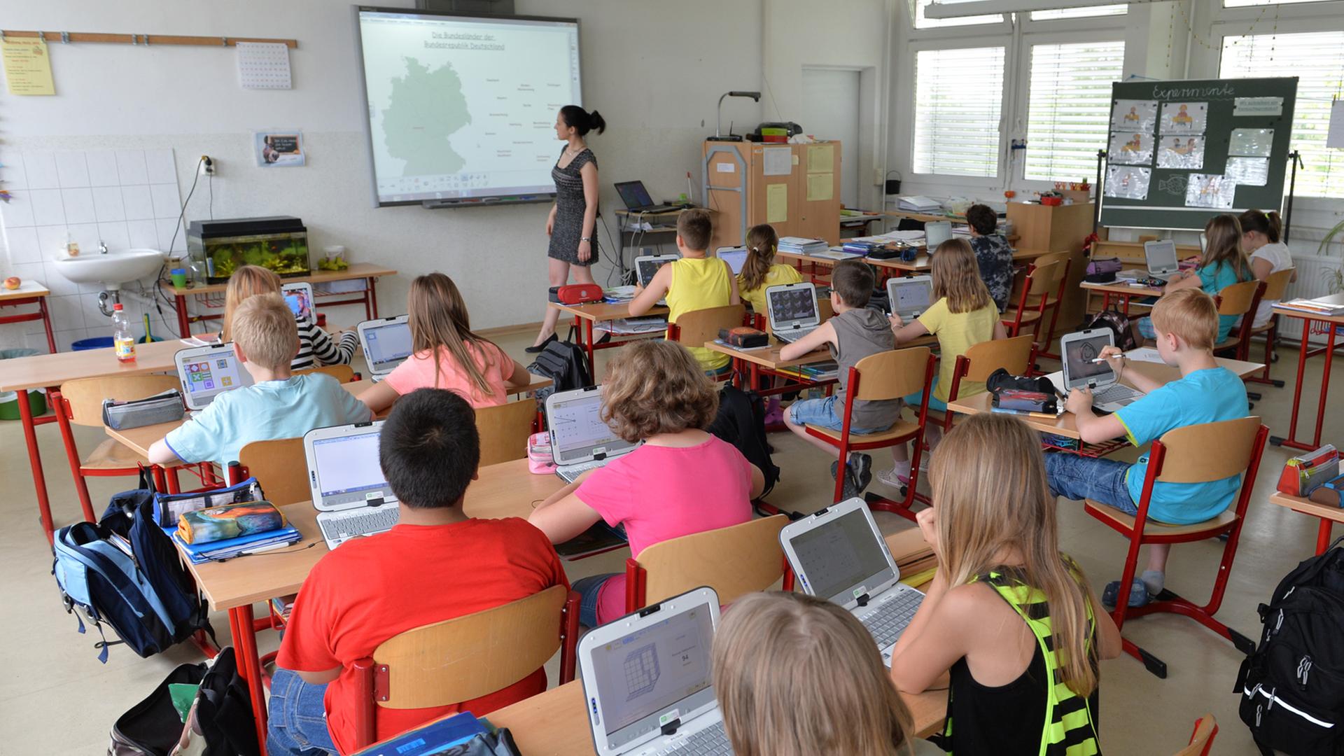 Schüler der vierten Klasse der Grundschule "Wilhelm Busch" Altenburg sitzen in Altenburg (Thüringen) in einem interaktiven Klassenzimmer vor ihren Laptops.