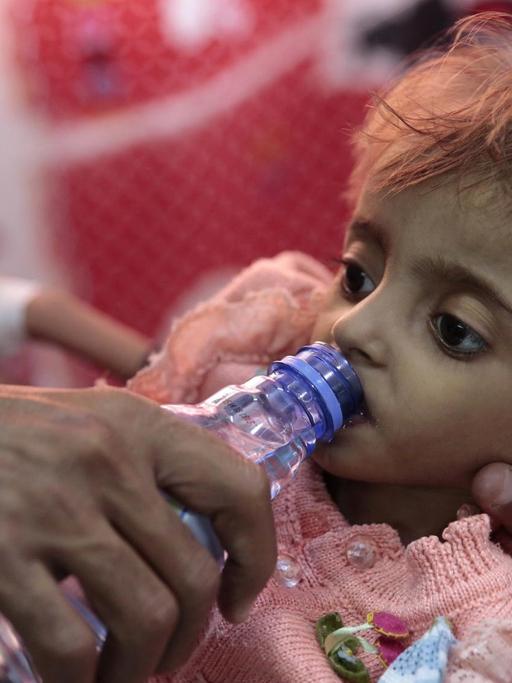 Ein Vater gibt seiner Tochter Wasser zu trinken in einem Hospital in Hodeida