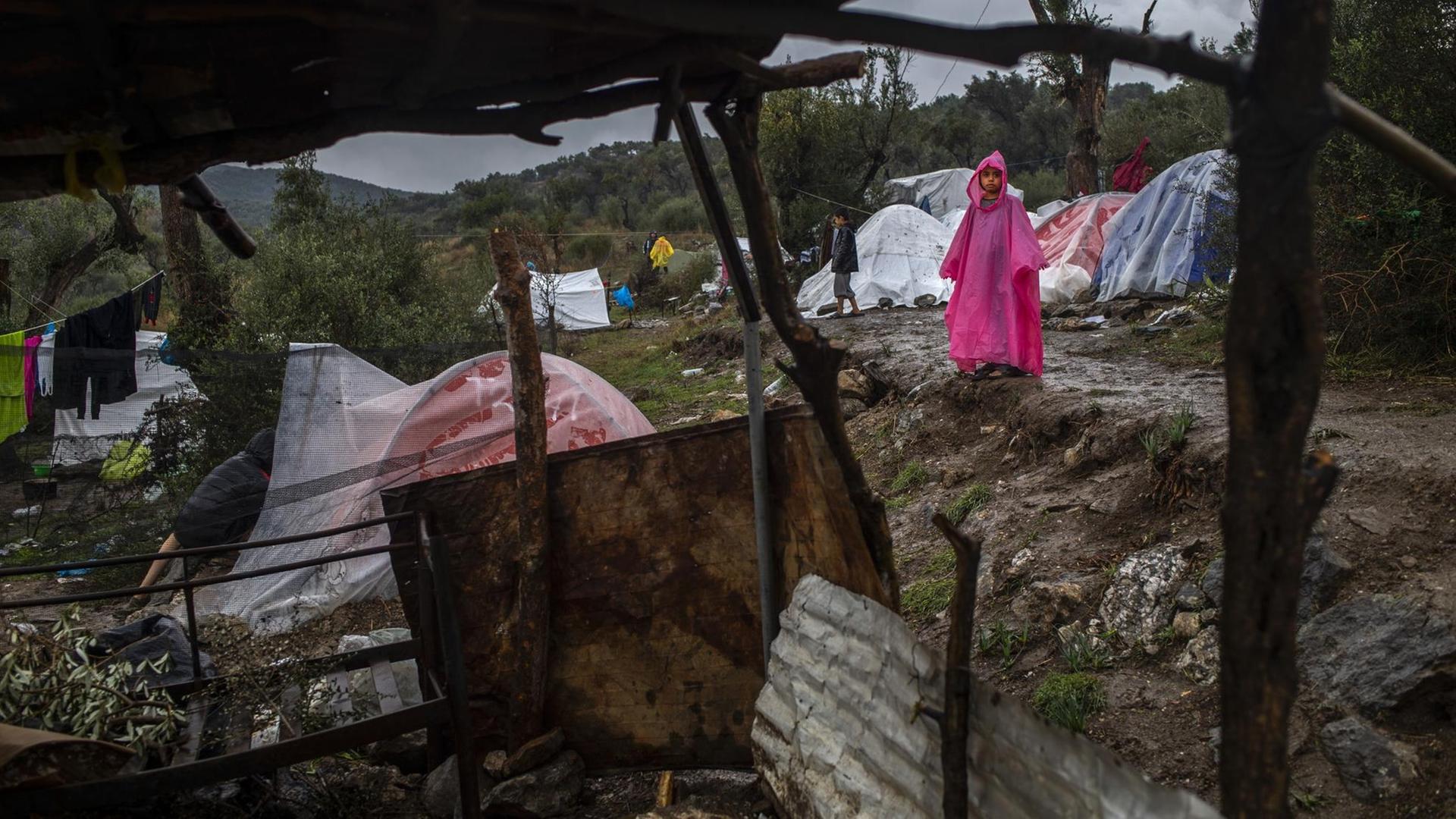 Ein junges Mädchen steht in einem provisorischen Lager neben dem Lager Moria auf Lesbos in Griechenland im Regen, aufgenommen im November 2019 Ein junges Mädchen steht in einem provisorischen Lager neben dem Lager Moria auf Lesbos in Griechenland im Regen, aufgenommen im November 2019