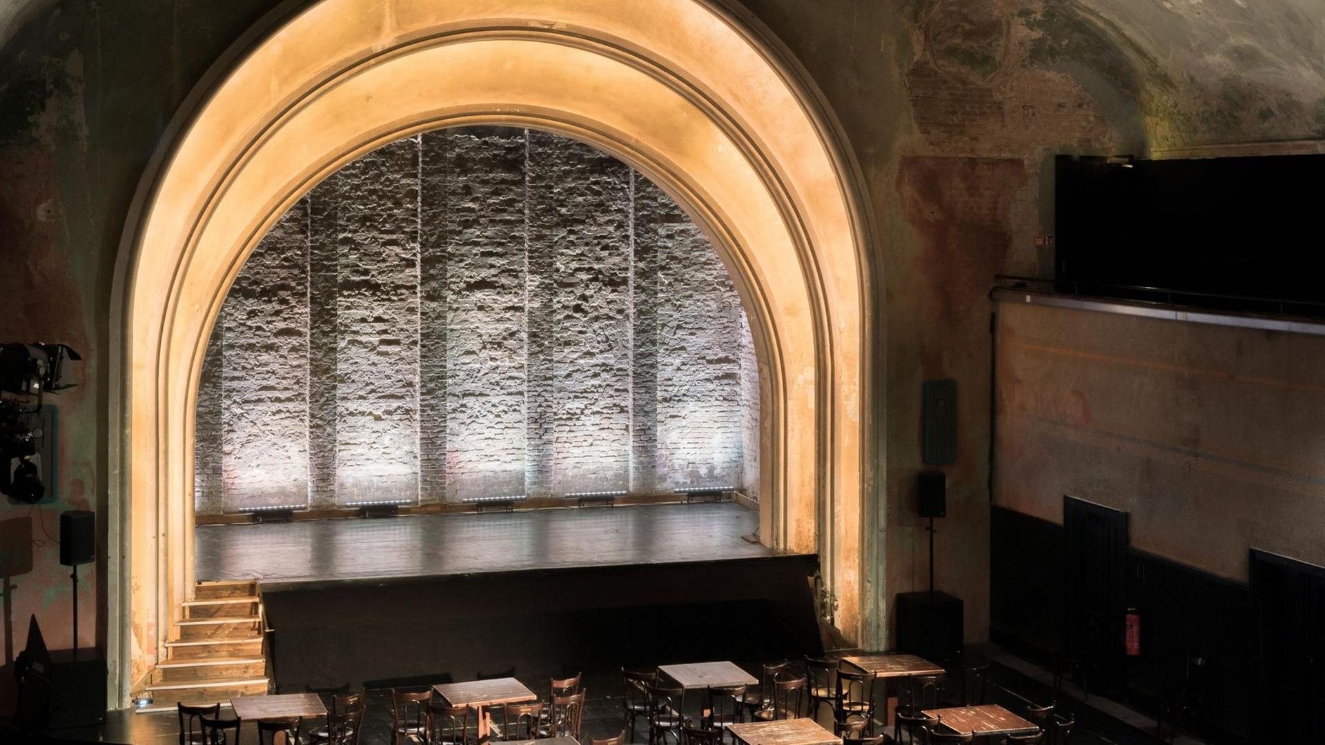 Ein großer, beleuchteter Bogen schwingt sich über die leere Bühne des Theaters. Ein großer, beleuchteter Bogen schwingt sich über die leere Bühne des Theaters.