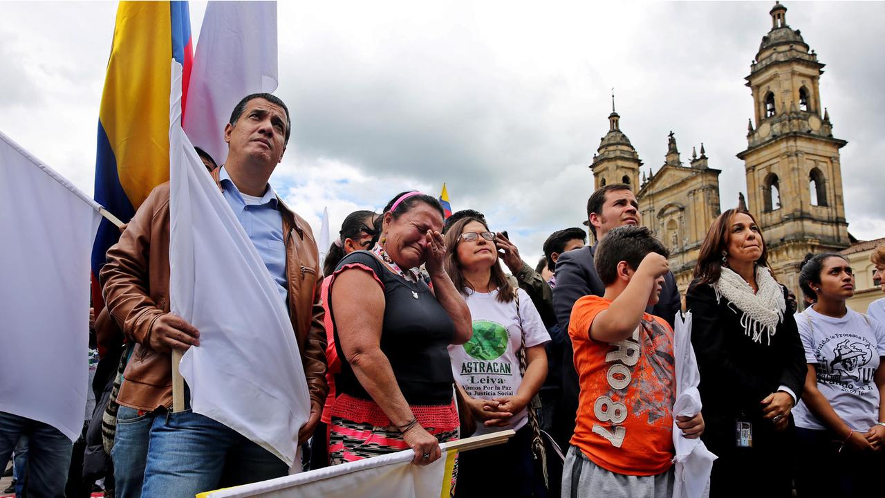 Zahlreiche Menschen sind zur Unterzeichnung des neuen Friedensabkommens zwischen der kolumbianischen Regierung und der FARC-Guerilla am 24.11.2016 in Bogota gekommen. Sie tragen Fahnen, manche weinen.