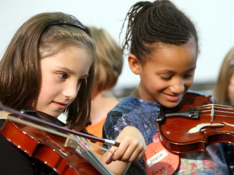 Zwei Grundschülerinnen aus Oberhausen probieren ihre neuen Geigen aus.
