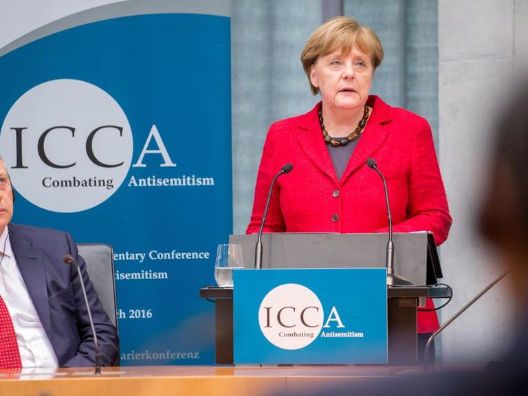 Bundeskanzlerin Angela Merkel (CDU) spricht am 14.03.2016 bei der ICCA Antisemitismus Konferenz in Berlin neben dem Vorsitzenden der ICCA, John Mann.