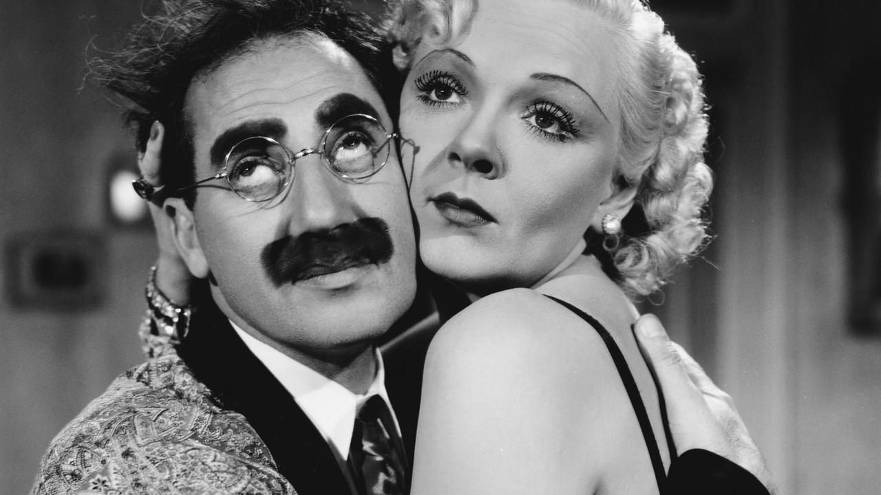 Groucho Marx und Esther Muir sitzen umschlungen auf einer Couch. Groucho Marx und Esther Muir sitzen umschlungen auf einer Couch.