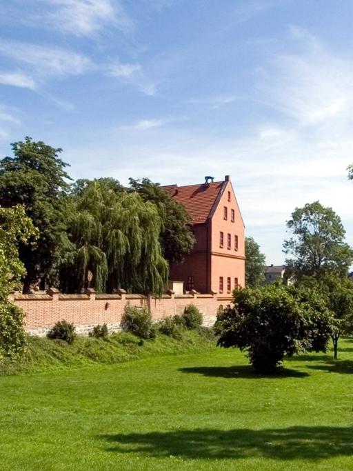 Ansicht der Alten Burg Penzlin und umliegender Wiesen an einem sonnigen Sommertag.