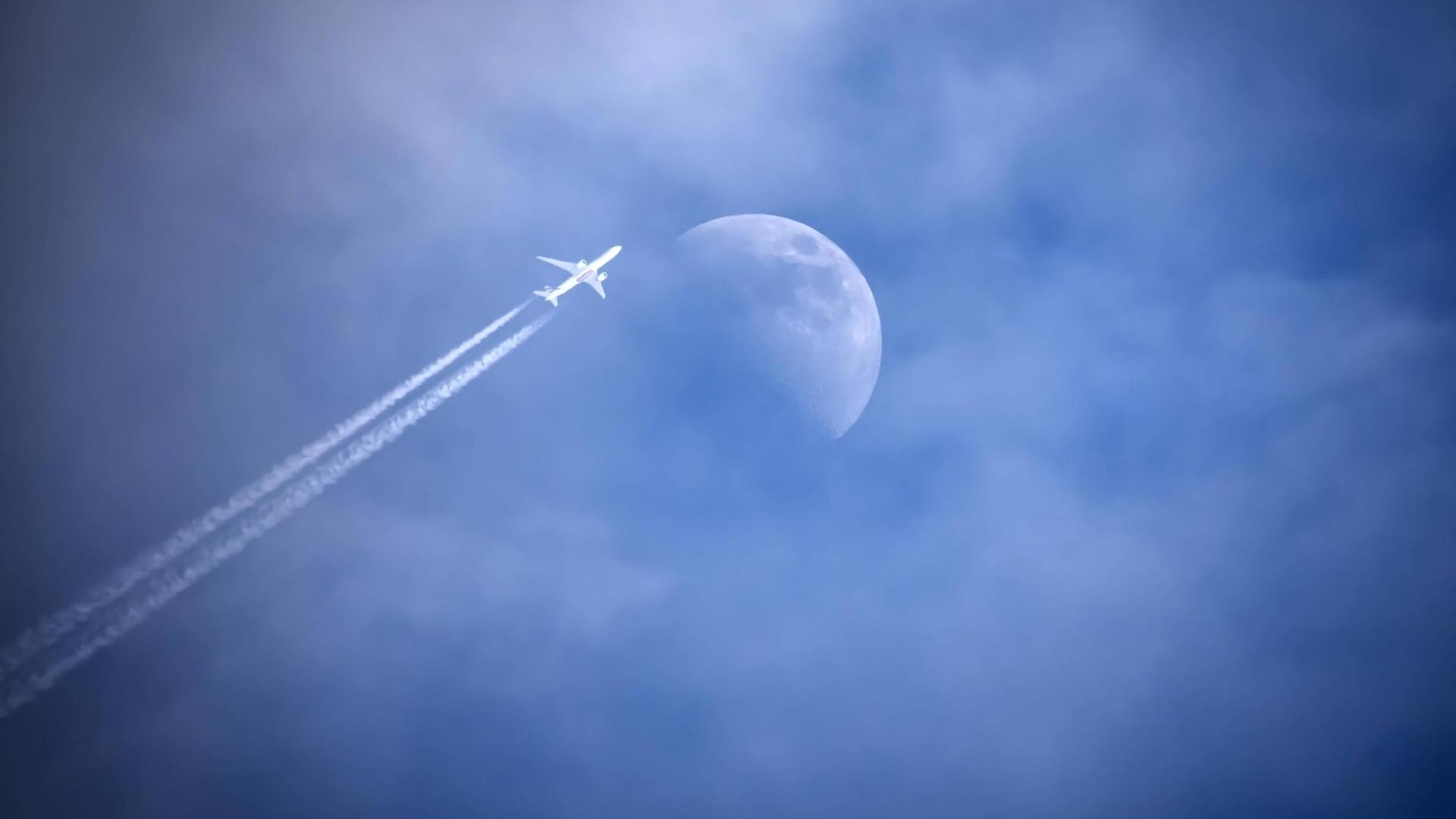 Flugzeug mit Kondensstreifen streift den Mond am Himmel. Flugzeug mit Kondensstreifen streift den Mond am Himmel.
