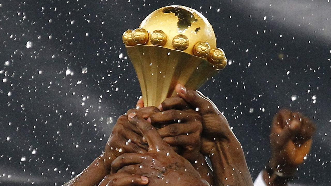 Mehrere Hände greifen nach der Trophäe des Afrika-Cups. Mehrere Hände greifen nach der Trophäe des Afrika-Cups.