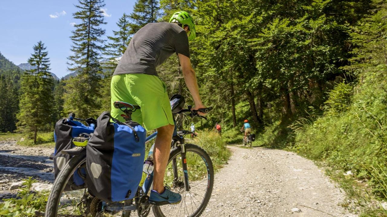 Ein Radfahrer bei der Alpenüberquerung auf einem Schotterweg Ein Radfahrer bei der Alpenüberquerung auf einem Schotterweg
