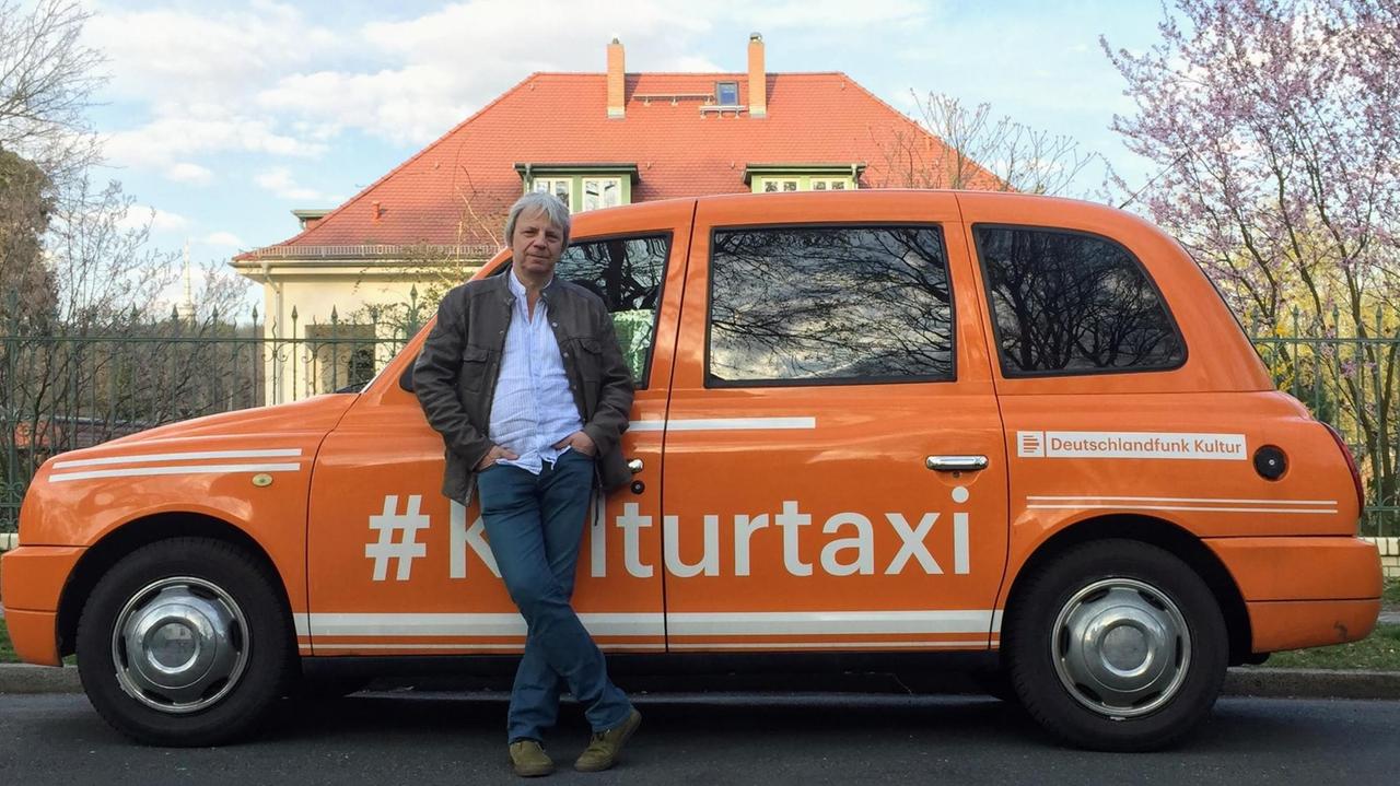 Andreas Dresen steht vor dem orangenen Kulturtaxi des Deutschlandfunks Kultur in Potsdam-Babelsberg. Andreas Dresen steht vor dem orangenen Kulturtaxi des Deutschlandfunks Kultur in Potsdam-Babelsberg.