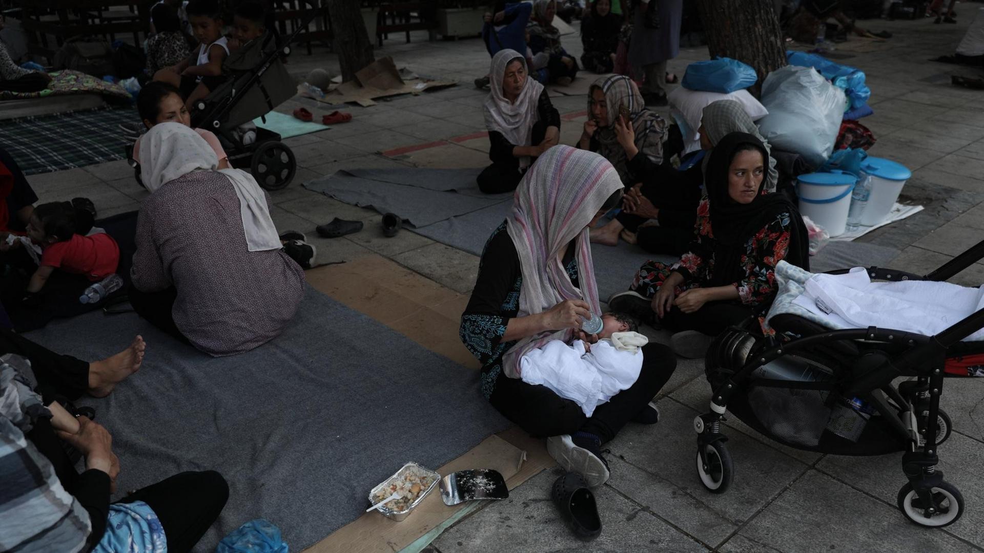 Flüchtlingsfrauen mit Kopftüchern sitzen auf Kartons und Decken auf dem Viktoria-Platz in Athen. Flüchtlingsfrauen mit Kopftüchern sitzen auf Kartons und Decken auf dem Viktoria-Platz in Athen.