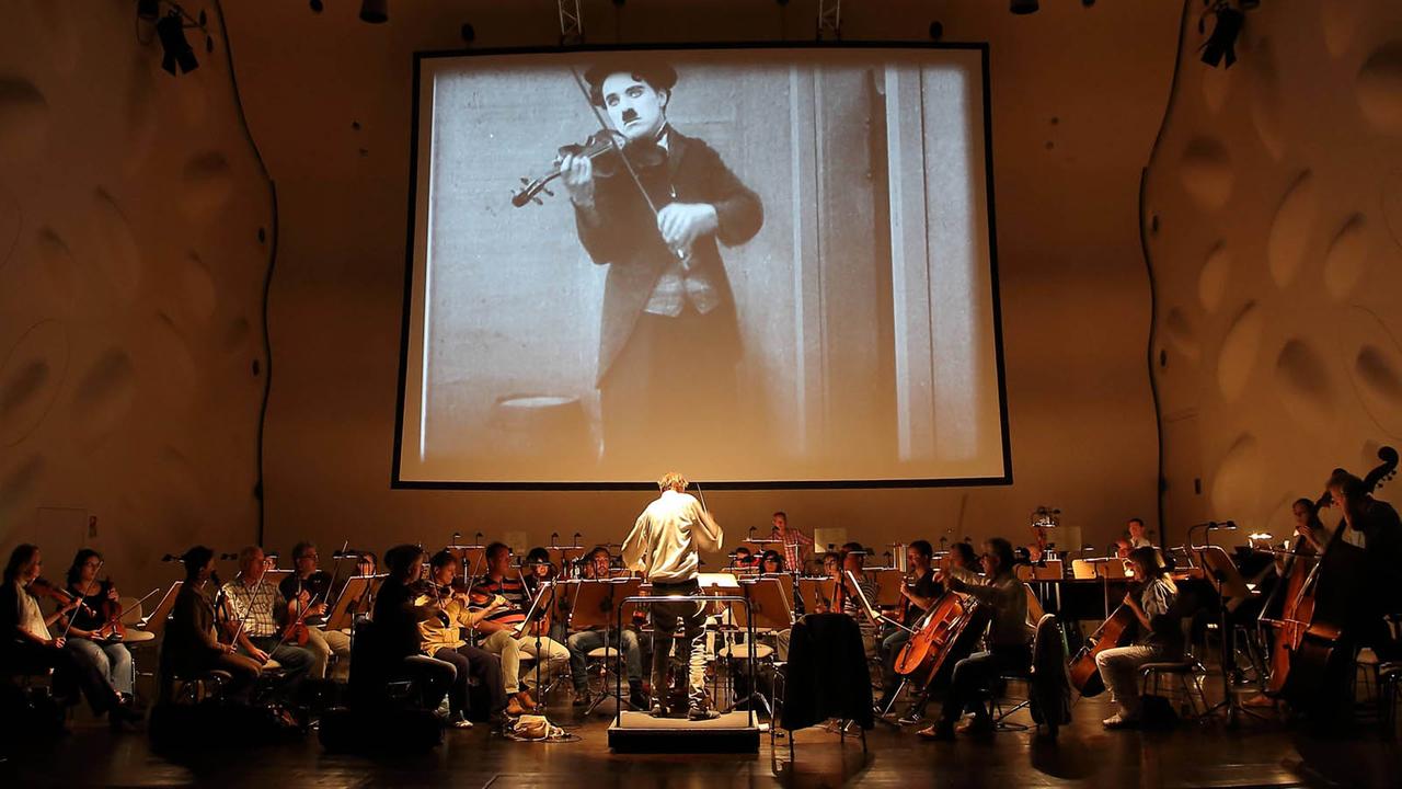 Das Filmorchester Babelsberg gibt ein Konzert in der Berliner Waldbühne. Im Hintergrund ist eine Szene aus einem "Harry Potter"-Film zu sehen, das Publikum verfolgt das Geschehen gebannt. Das Filmorchester Babelsberg gibt ein Konzert in der Berliner Waldbühne. Im Hintergrund ist eine Szene aus einem "Harry Potter"-Film zu sehen, das Publikum verfolgt das Geschehen gebannt.