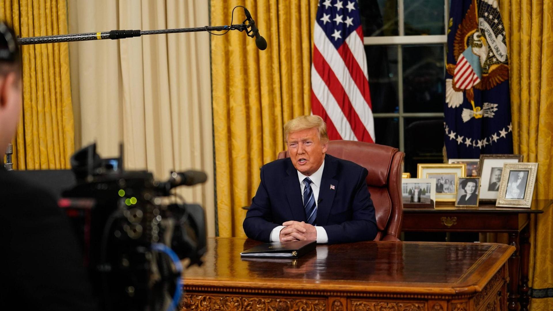 US-Präsident Donald Trump hat die Einreisesperren für Menschen aus dem europäischen Schengenraum in einer Fernsehansprache verkündet. Eine Kamera filmt ihn an seinem Schreibtisch im Oval Office im Weißen Haus in Washington. US-Präsident Donald Trump hat die Einreisesperren für Menschen aus dem europäischen Schengenraum in einer Fernsehansprache verkündet. Eine Kamera filmt ihn an seinem Schreibtisch im Oval Office im Weißen Haus in Washington.