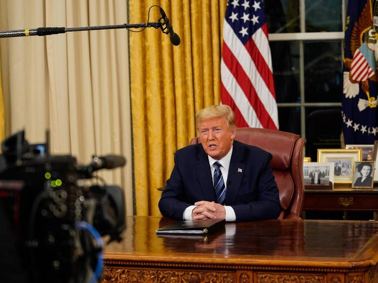US-Präsident Donald Trump hat die Einreisesperren für Menschen aus dem europäischen Schengenraum in einer Fernsehansprache verkündet. Eine Kamera filmt ihn an seinem Schreibtisch im Oval Office im Weißen Haus in Washington.