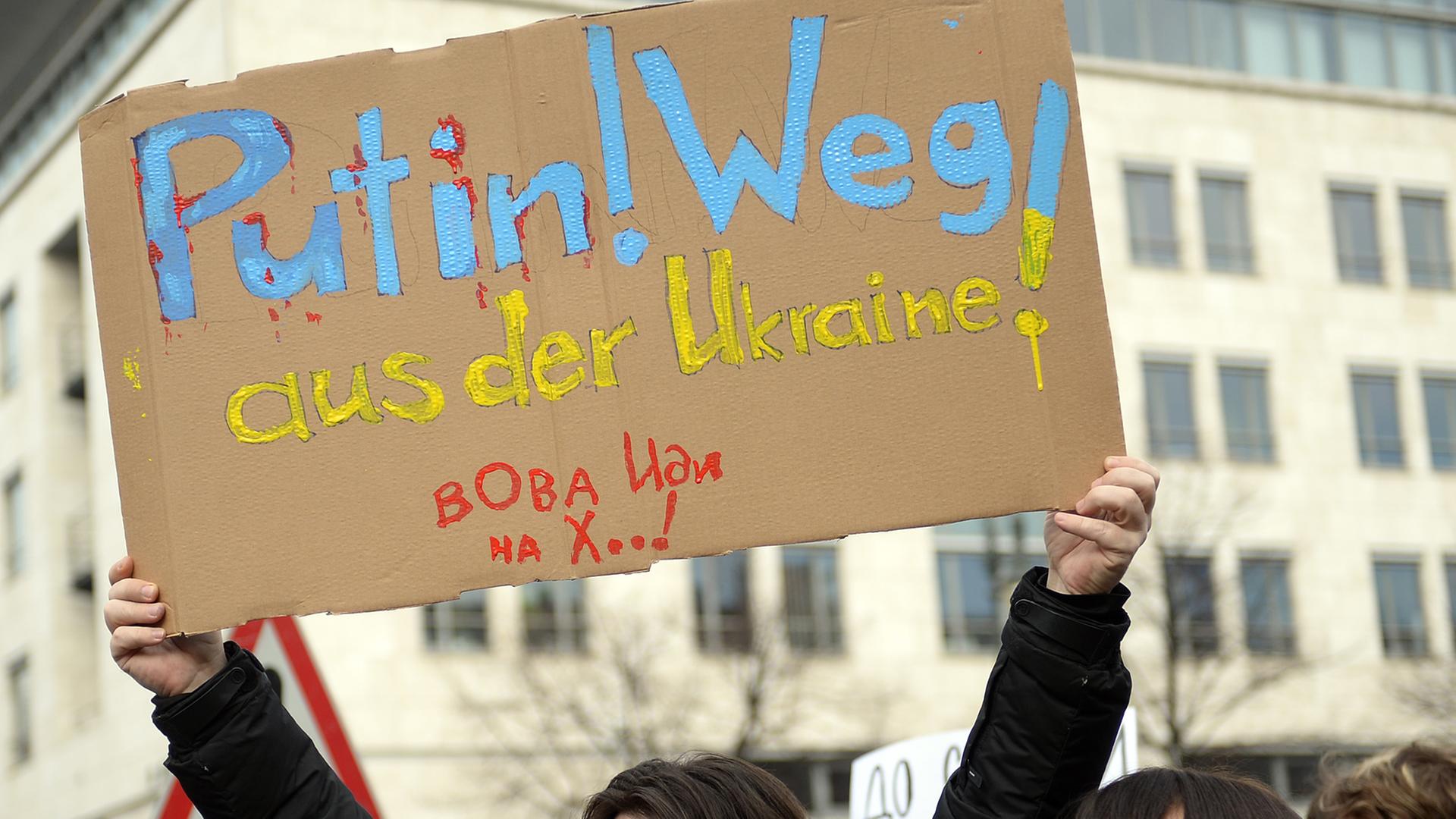 Ein Demonstrant zeigt am 02.03.2014 vor der russischen Botschaft in Berlin ein Plakat mit der Aufschrift "Putin! Weg! aus der Ukraine". Ein Demonstrant zeigt am 02.03.2014 vor der russischen Botschaft in Berlin ein Plakat mit der Aufschrift "Putin! Weg! aus der Ukraine".