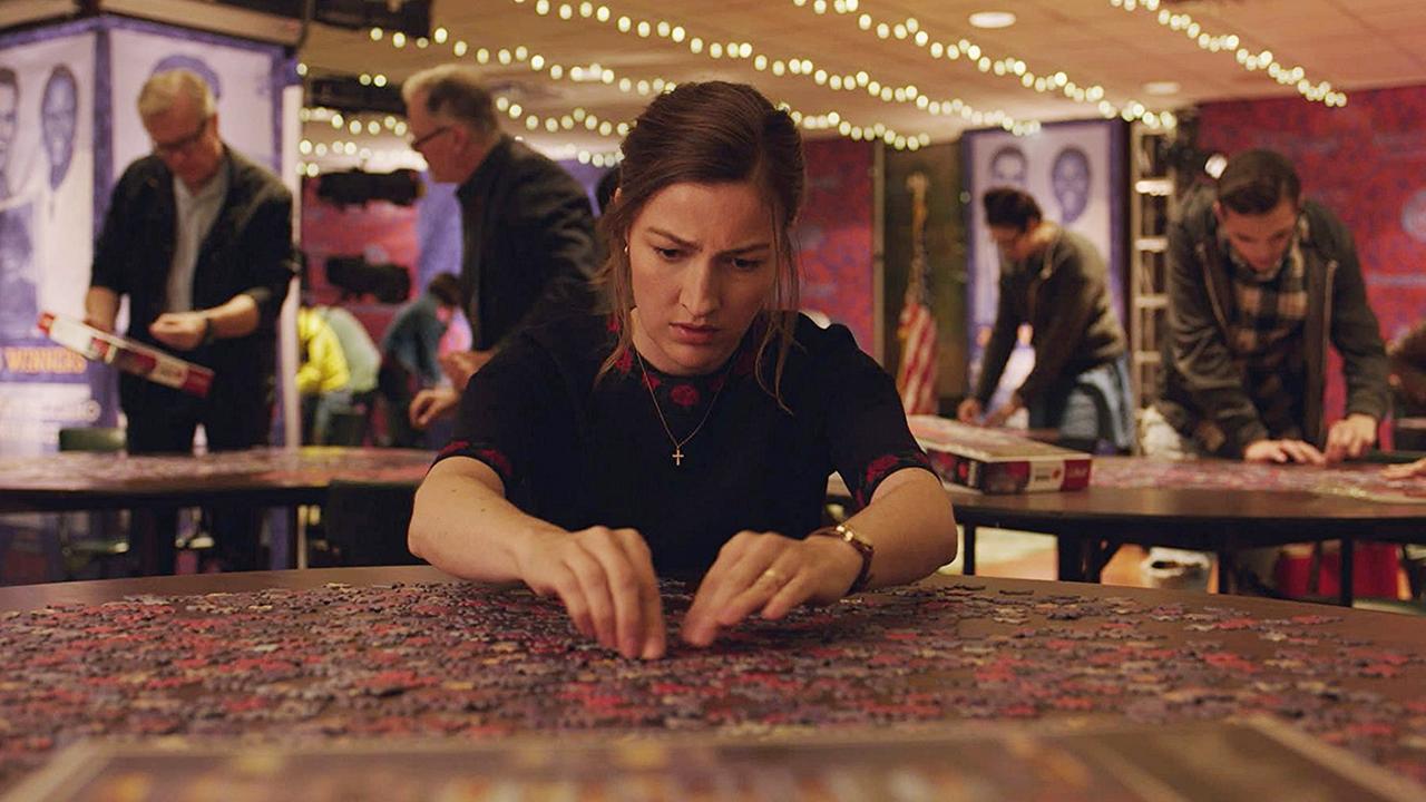 Eine Frau sitzt an einem Tisch und löst gebannt ein Puzzle. Eine Frau sitzt an einem Tisch und löst gebannt ein Puzzle.