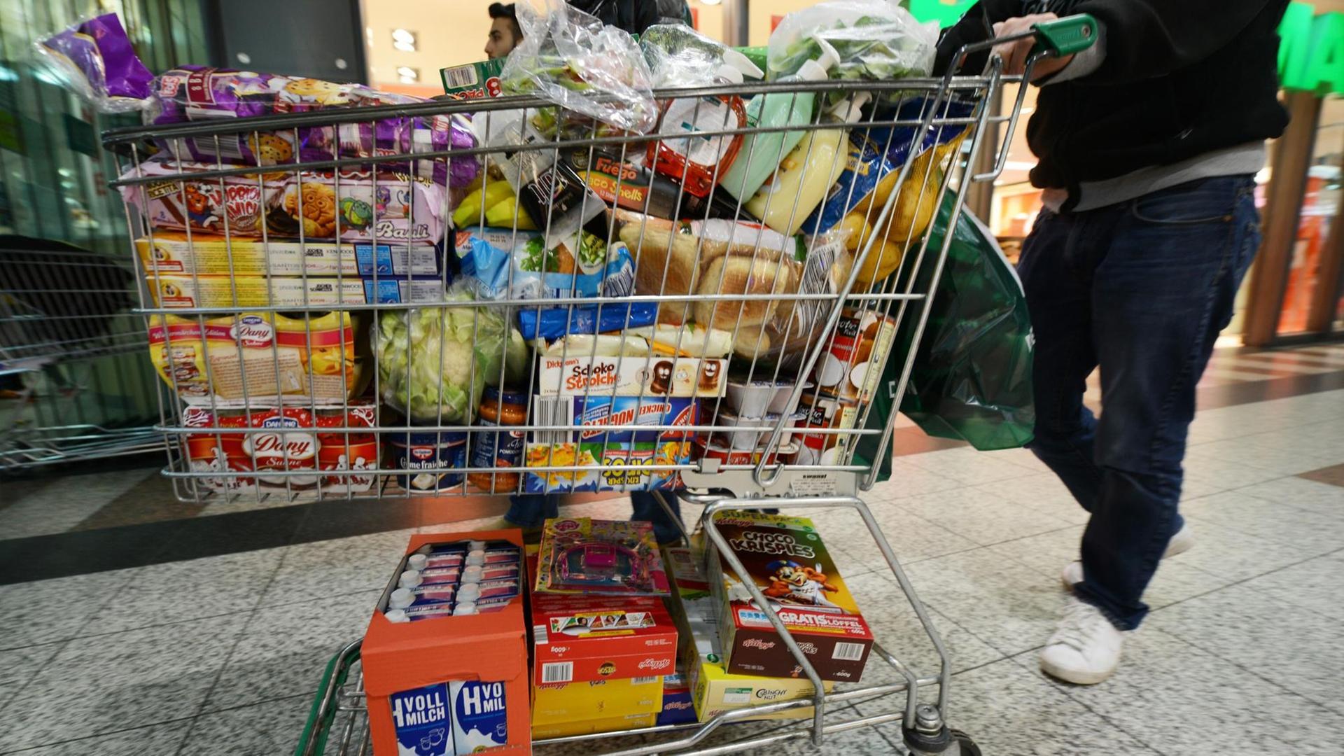 Ein Mann schiebt einen vollgepackten Einkaufswagen. Ein Mann schiebt einen vollgepackten Einkaufswagen.