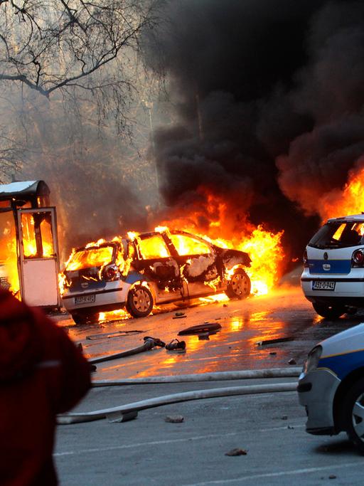 Dunkler Rauch steigt über brennenden Polizeiautos in Sarajevo auf.