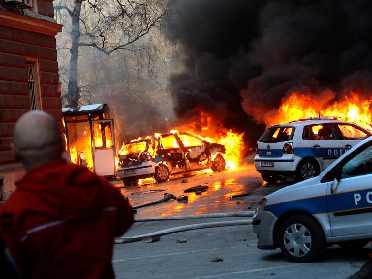 Dunkler Rauch steigt über brennenden Polizeiautos in Sarajevo auf.