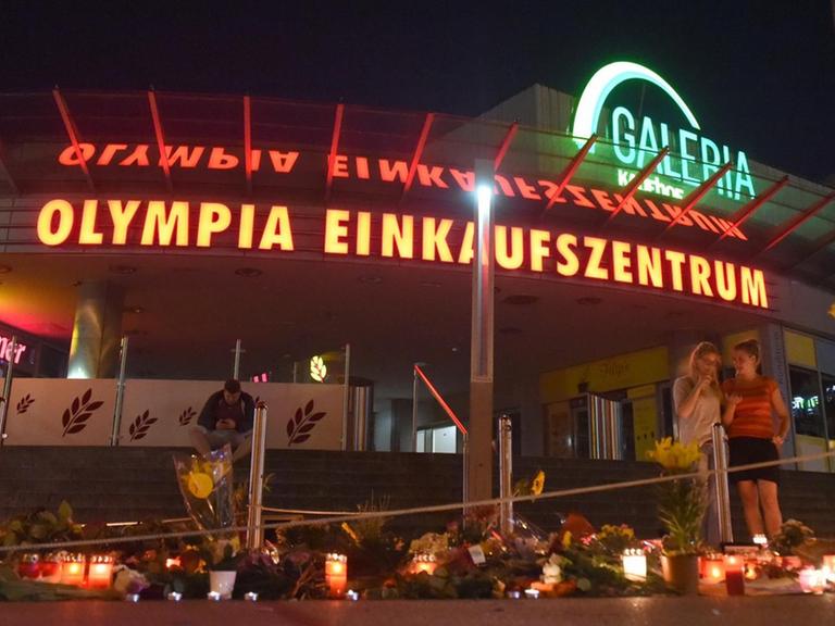 Vor dem Olympia Einkaufszentrum liegen Blumen, es brennen Kerzen.