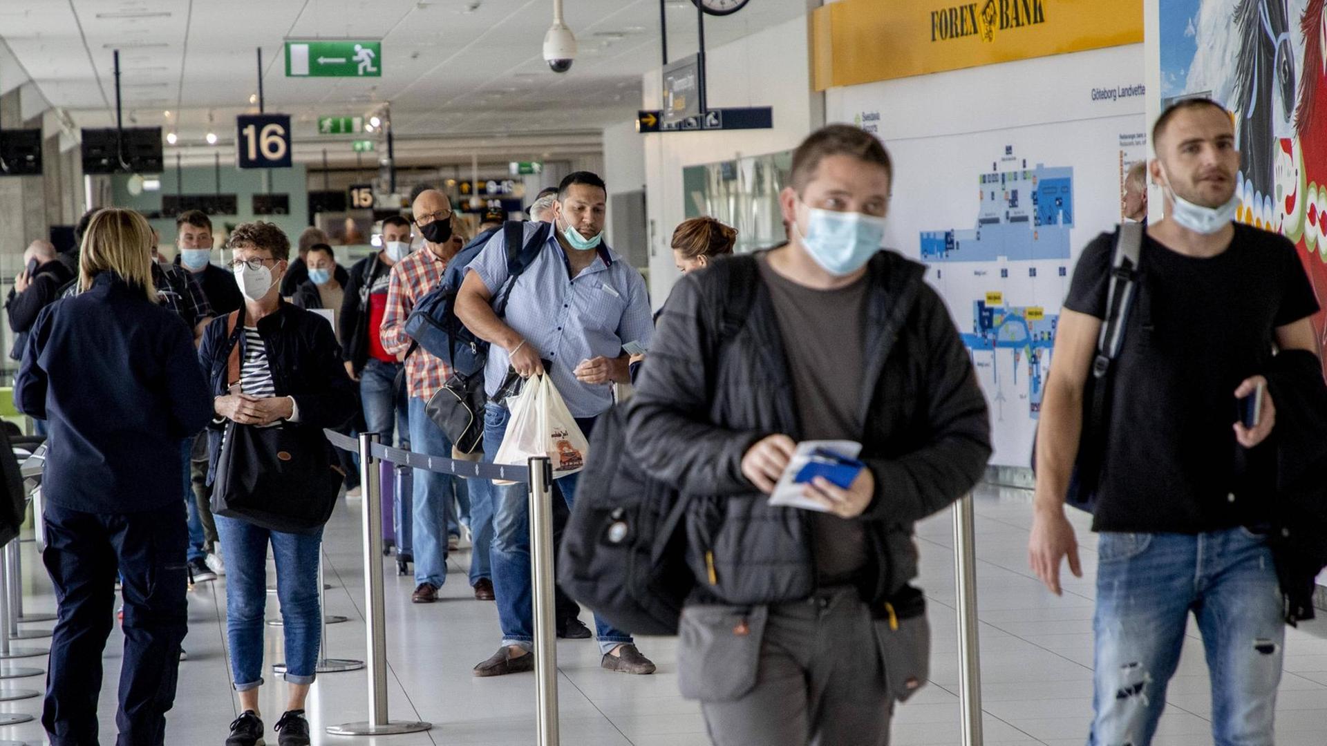 Flug-Passagiere mit Mundschutz laufen durch den Frankfurter Flughafen. Flug-Passagiere mit Mundschutz laufen durch den Frankfurter Flughafen.