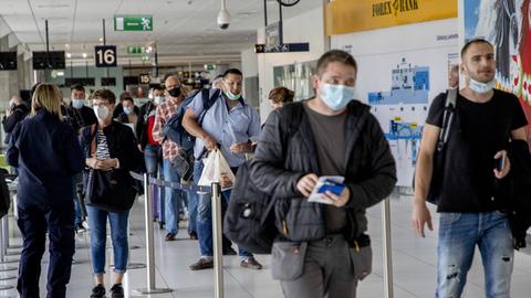 Flug-Passagiere mit Mundschutz laufen durch den Frankfurter Flughafen.