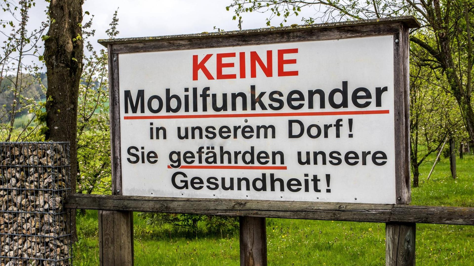 Auf einem Protestschild steht: Keine Mobilfunksender in unserem Dorf! Sie gefährden unsere Gesundheit! Auf einem Protestschild steht: Keine Mobilfunksender in unserem Dorf! Sie gefährden unsere Gesundheit!