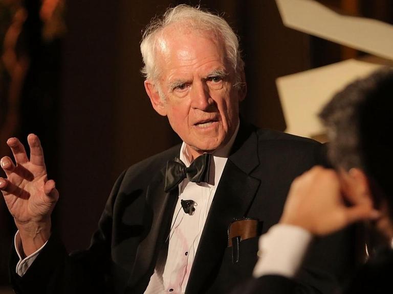 Charles Taylor sitzt auf einer Bühne und unterhält sich mit einem Moderator.