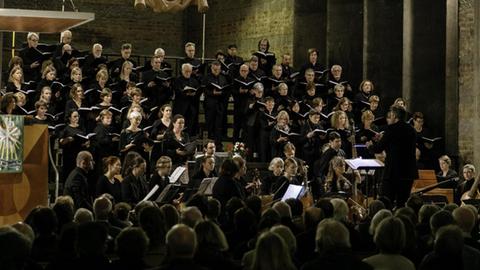 Das Bild zeigt den Chor bei einem Auftritt in der Kirche. Im Vordergrund ist das Publikum von hinten zu sehen.