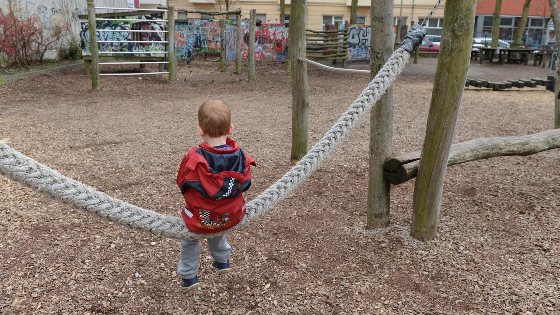 Ein Junge sitzt alleine auf einer Schaukel auf einem Spielplatz in Berlin Ein Junge sitzt alleine auf einer Schaukel auf einem Spielplatz in Berlin