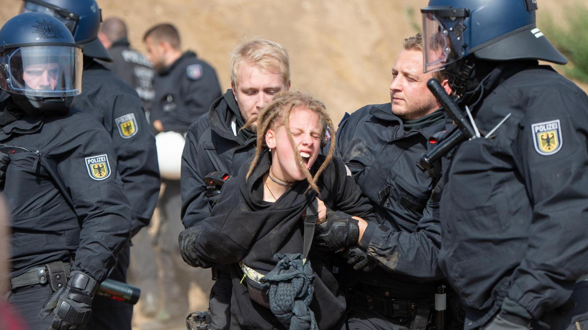 Das Bild zeigt Polizisten, die im Hambacher Forst eine Demonstrantin festnehmen.