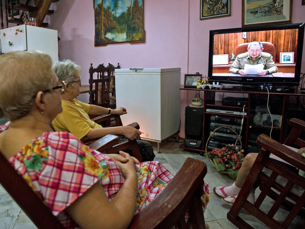 Mehrere kubanische Frauen sitzen vor dem Fernseher, in dem Staatspräsident Raúl Castro bei einer Ansprache zu sehen ist. Mehrere kubanische Frauen sitzen vor dem Fernseher, in dem Staatspräsident Raúl Castro bei einer Ansprache zu sehen ist.