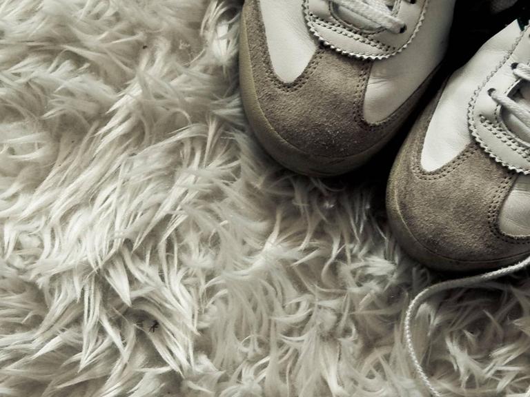 Turnschuhe auf Flokatiteppich.