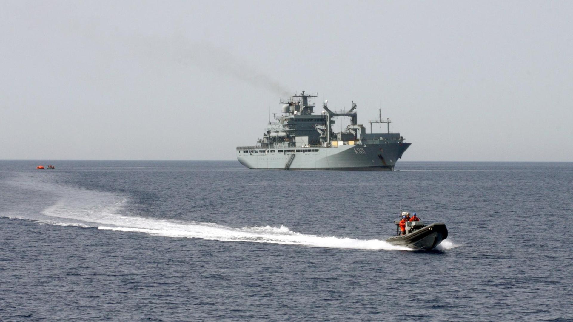Das graue Kriegsschiff setzt ein kleines Rettungsboot aus. Das graue Kriegsschiff setzt ein kleines Rettungsboot aus.
