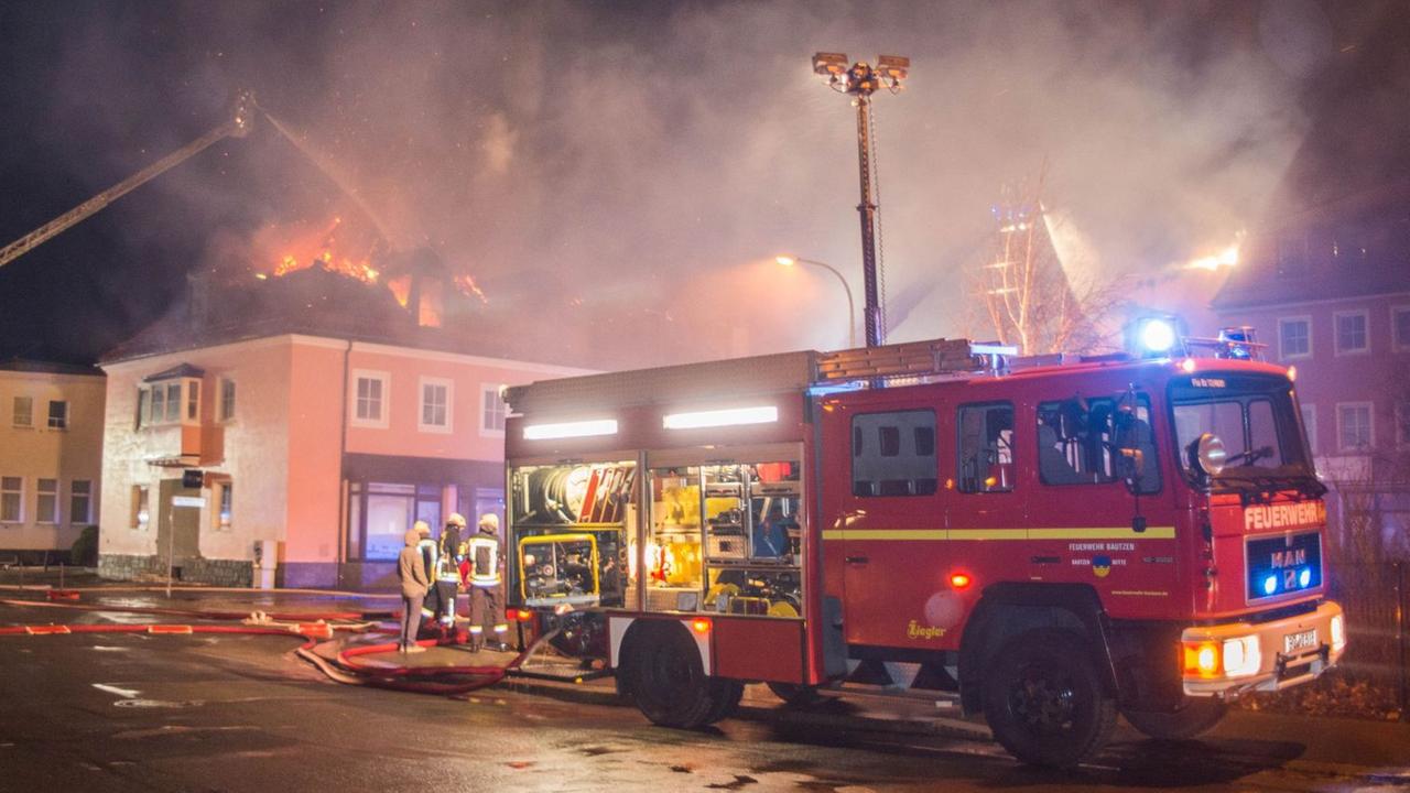 Ein Feuerwehrfahrzeug steht am 21.02.2016 in Bautzen (Sachsen) vor einem brennenden Haus. In einer geplanten Flüchtlingsunterkunft war in der Nacht zu Sonntag ein Feuer ausgebrochen. Foto: Rico Löb/dpa Ein Feuerwehrfahrzeug steht am 21.02.2016 in Bautzen (Sachsen) vor einem brennenden Haus. In einer geplanten Flüchtlingsunterkunft war in der Nacht zu Sonntag ein Feuer ausgebrochen. Foto: Rico Löb/dpa